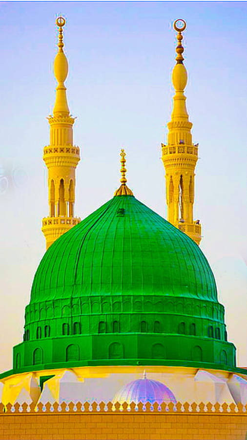 Madina 桌布 壁紙 — 一座充滿活力的綠色圓頂清真寺，金色宣禮塔在清澈的藍天下高聳。