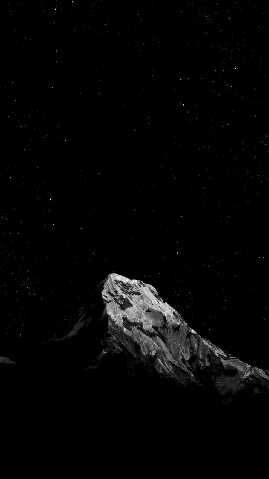  壁紙 — 一座單色調的山峰在繁星點點的夜空下聳立，帶有深邃陰影和鋒利山脊。