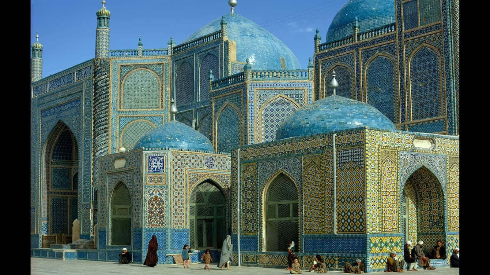 Afghanistan 桌布 壁紙 — 一座宏偉的伊斯蘭清真寺，擁有充滿活力的藍色瓷磚圓頂和精緻的幾何圖案，在清澈的藍天下。