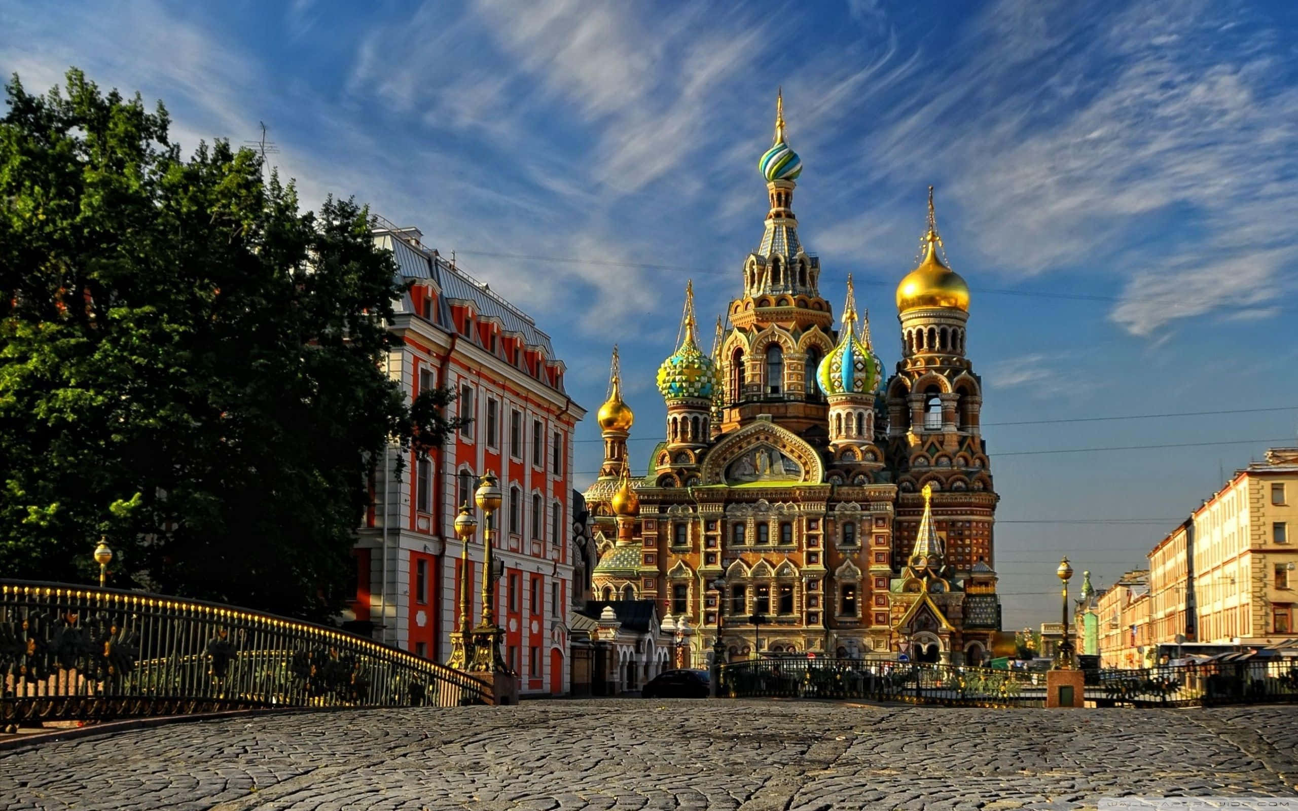 Russia 桌布 壁紙 — 一座宏偉的俄羅斯東正教教堂，擁有金色和多彩的圓頂，矗立在明亮藍天和縷縷白雲下。