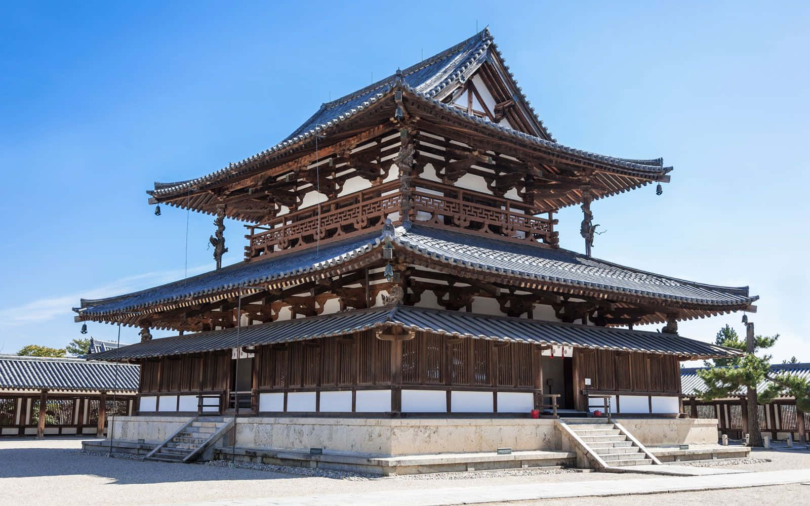 Japanese 桌布 壁紙 — 一座宏偉的傳統日本寺廟，擁有層疊的木造屋頂和瓦片屋簷，矗立在清澈的藍天下。