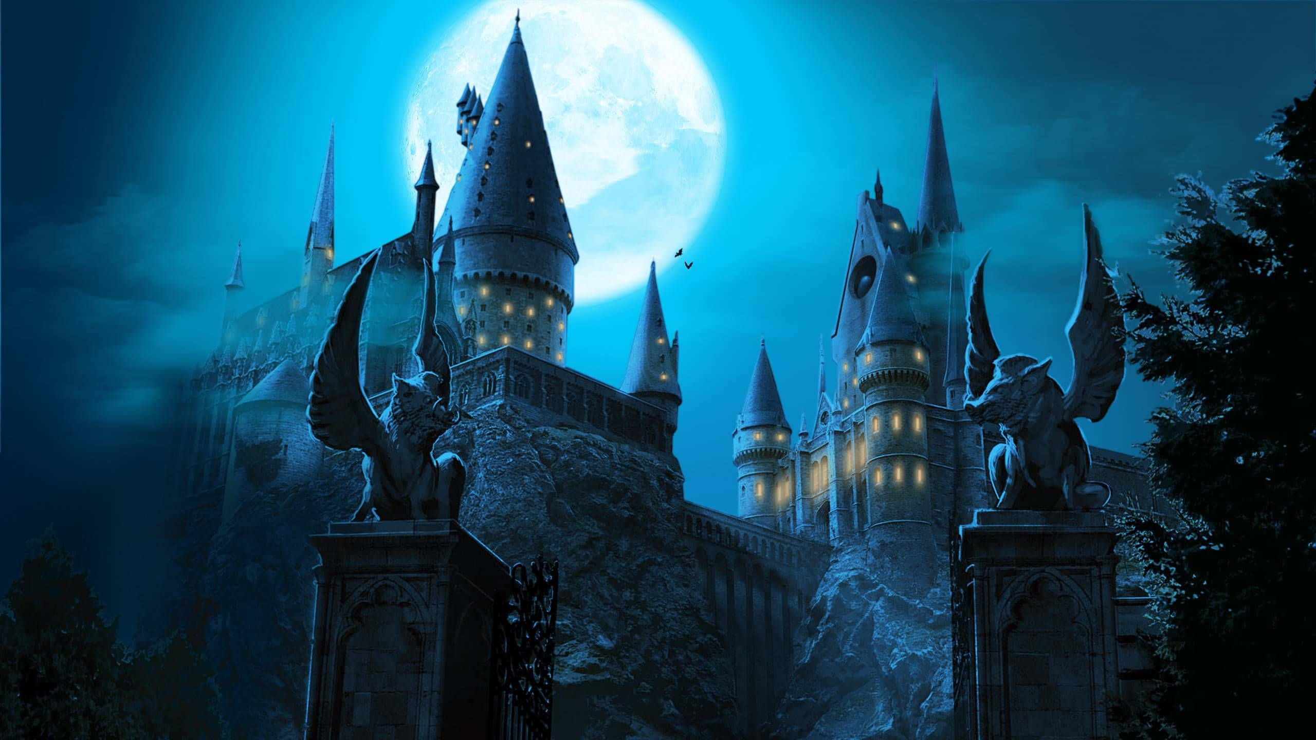 The Philosopher's Stone 桌布 壁紙 — 一座宏偉的哥德式城堡，窗戶發光，矗立在巨大的滿月下，周圍環繞著黑暗的樹木和有翼雕像。
