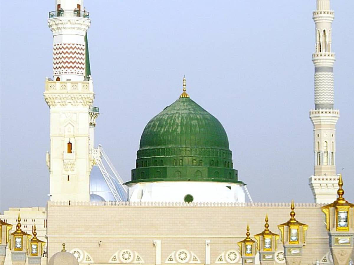 Madina Sharif 桌布 壁紙 — 一座宏偉的清真寺，擁有充滿活力的綠色圓頂和兩座高大的白色宣禮塔，在清澈的藍天下。