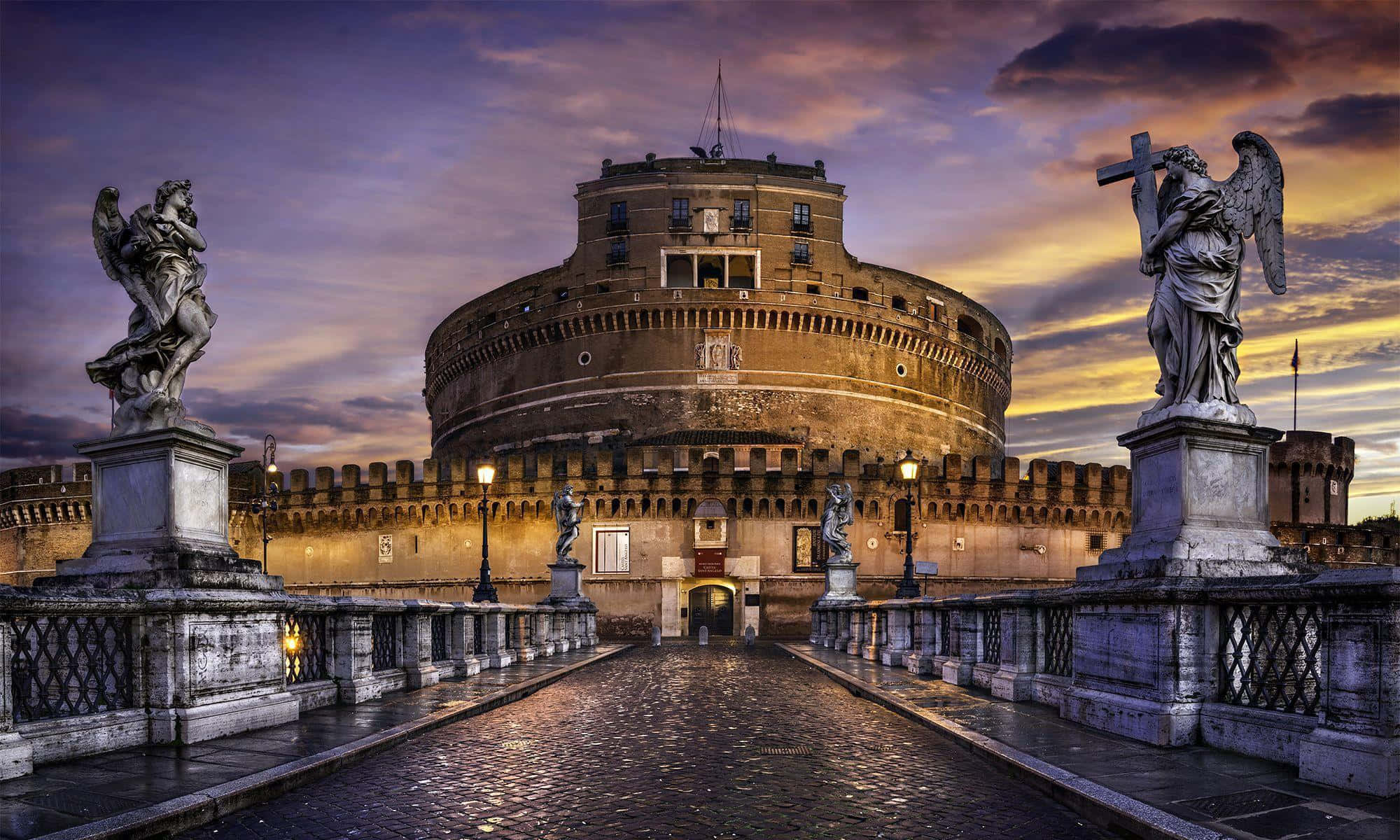 Rome 桌布 壁紙 — 一座宏偉的石頭堡壘矗立在戲劇性的暮色天空下，雕像守衛著通往入口的鵝卵石橋。