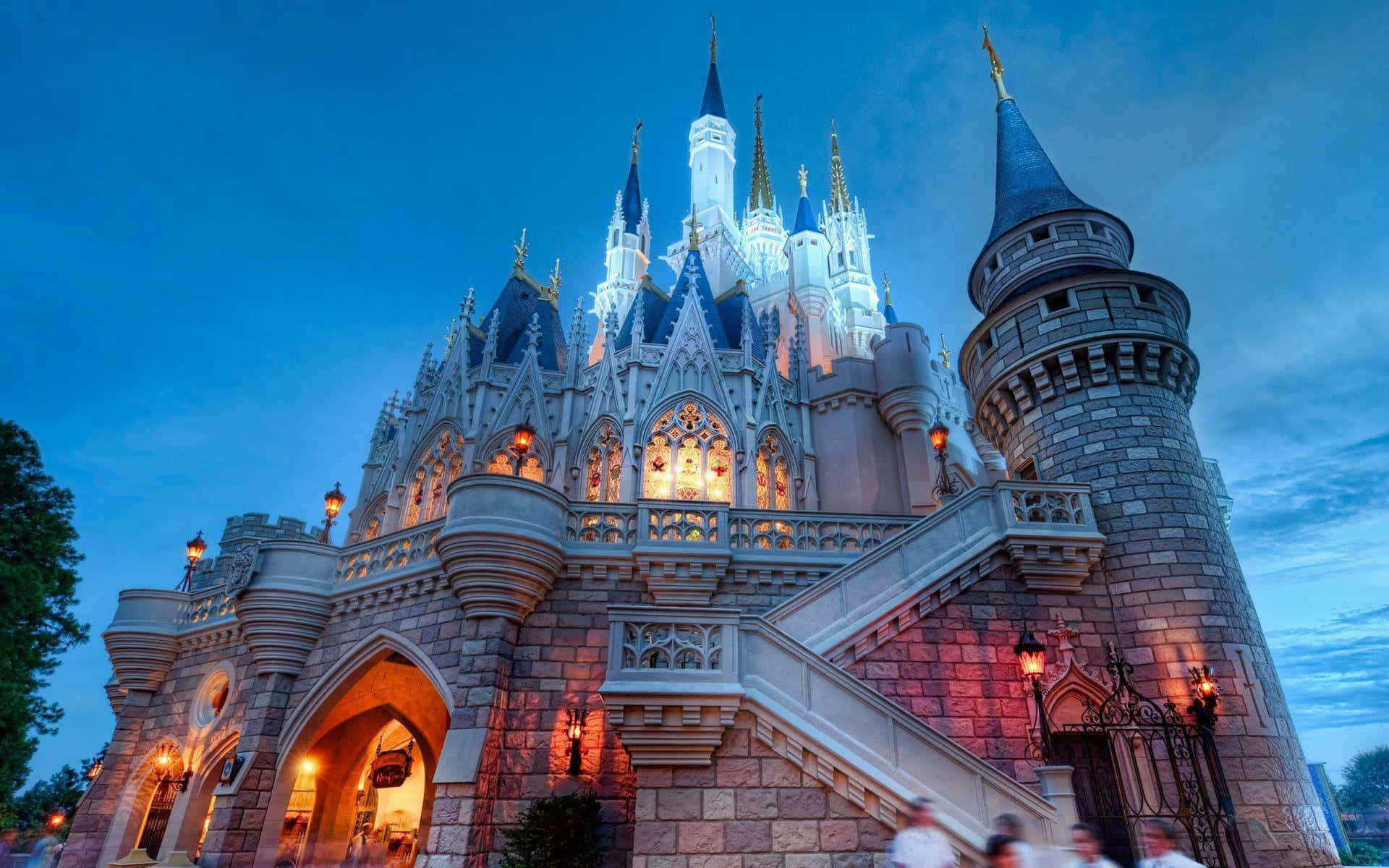 Disneyland 桌布 壁紙 — 一座宏偉的迪士尼城堡，藍色尖頂和溫暖燈光在暮色天空中閃耀。