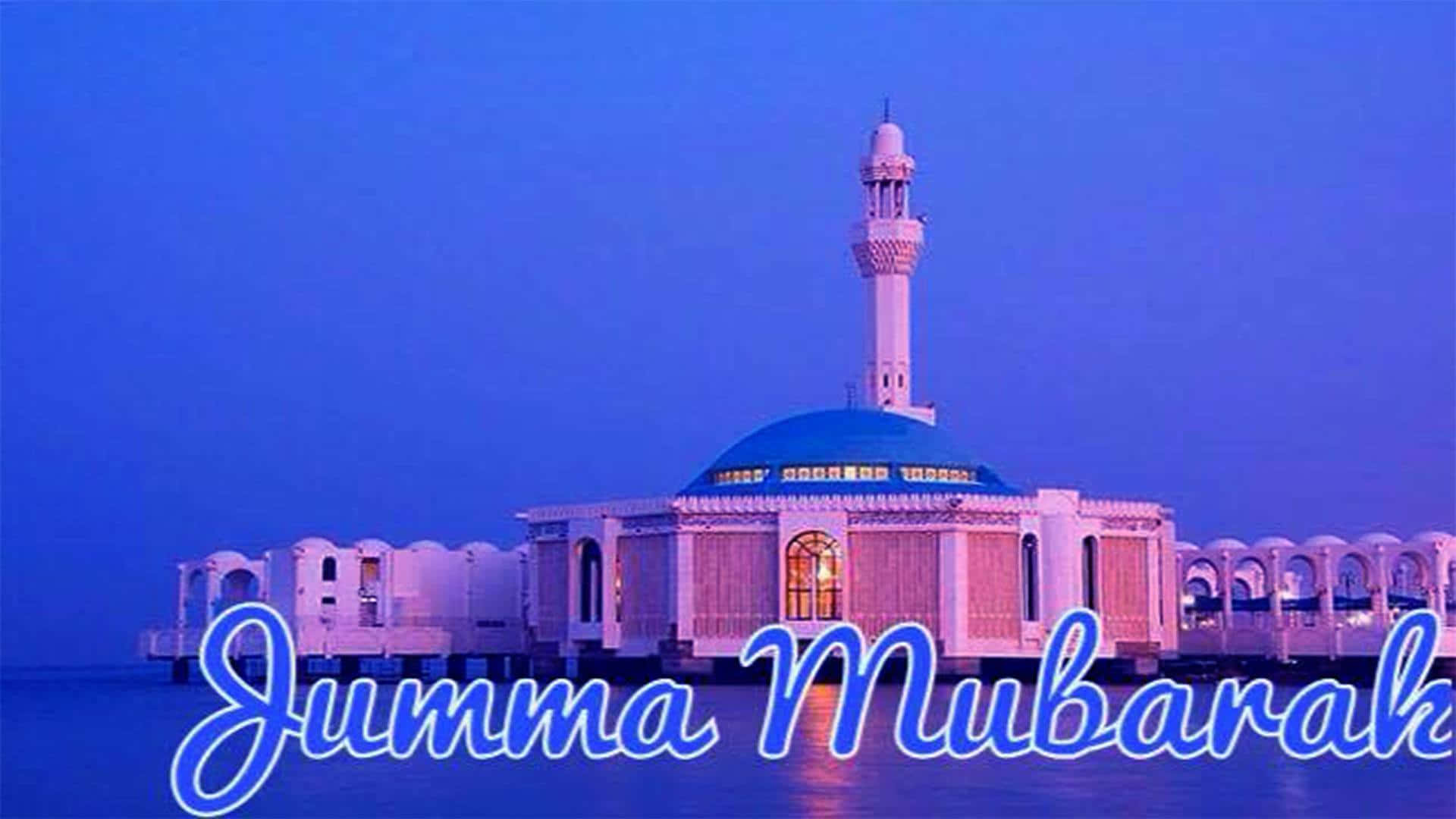 Jumma Mubarak 桌布 壁紙 — 一座寧靜的清真寺，擁有藍色圓頂和宣禮塔，在黃昏時分矗立在水面上，在紫色和藍色色調下閃耀，帶有「Jumma Mubarak」文字。