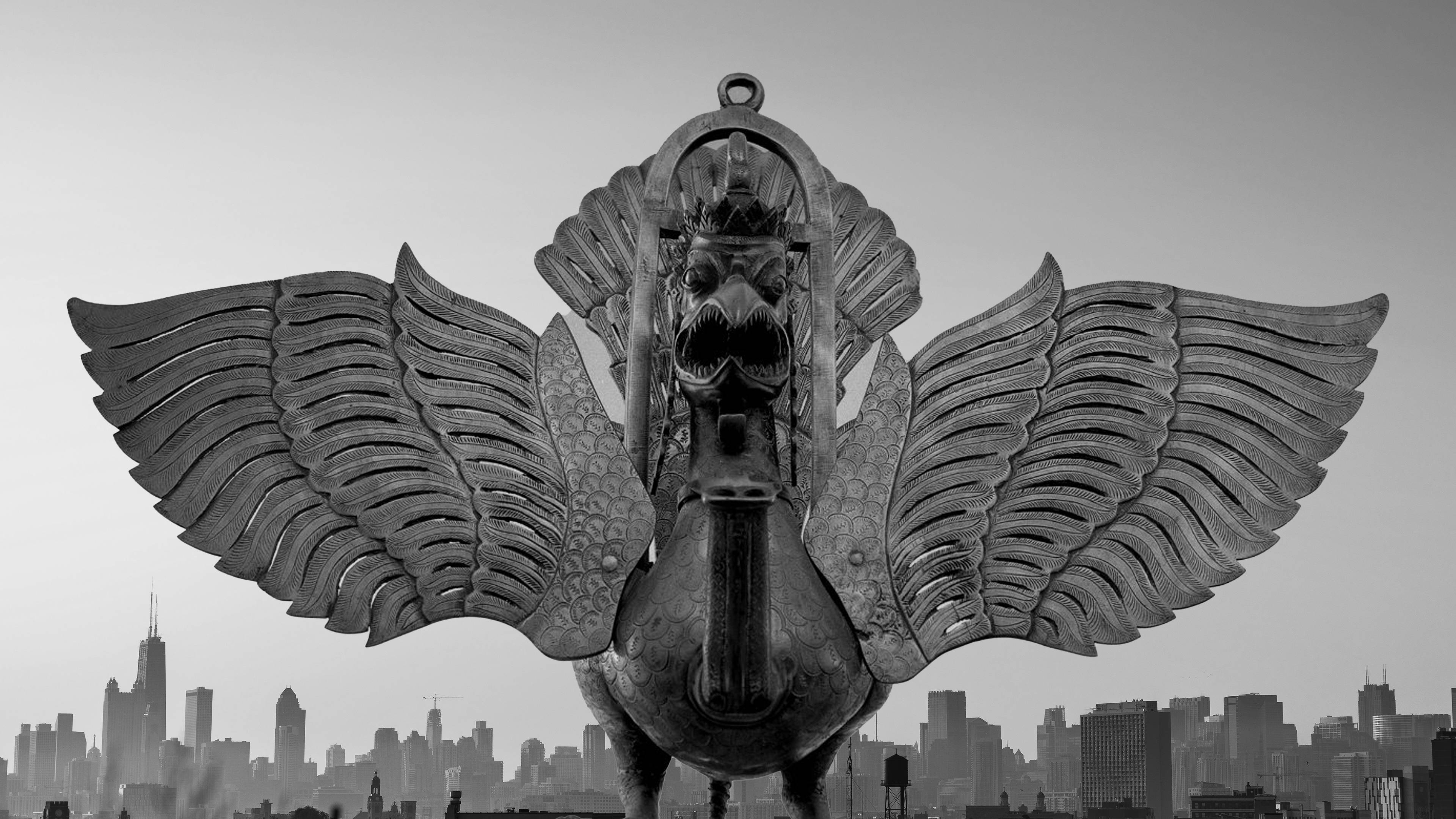 Garuda 桌布 壁紙 — 一座巨大的單色獅鷲雕像展開翅膀，在朦朧的天空下聳立於城市天際線之上。