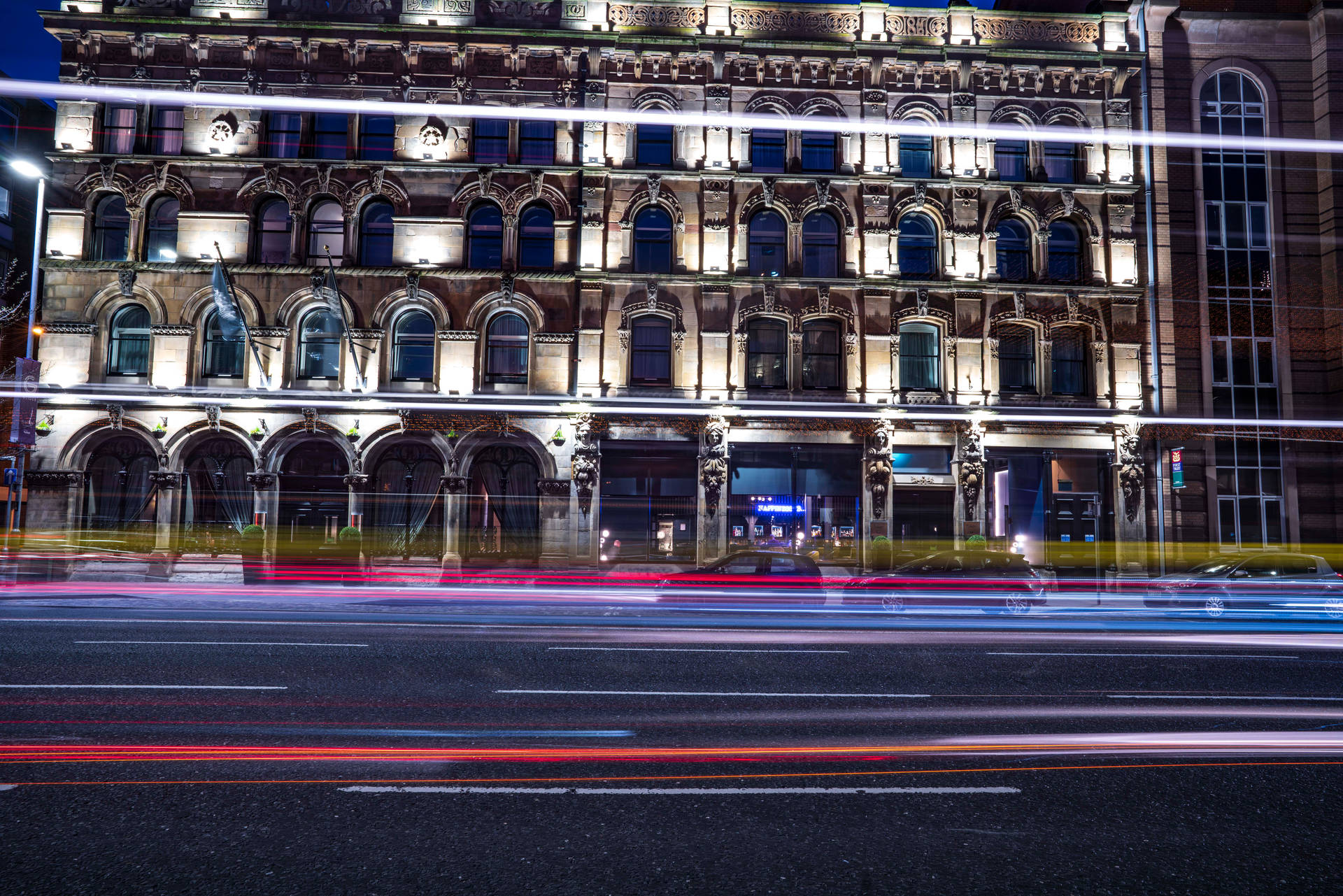夜間城市景觀，歷史建築和模糊的車燈劃過濕漉漉的街道。