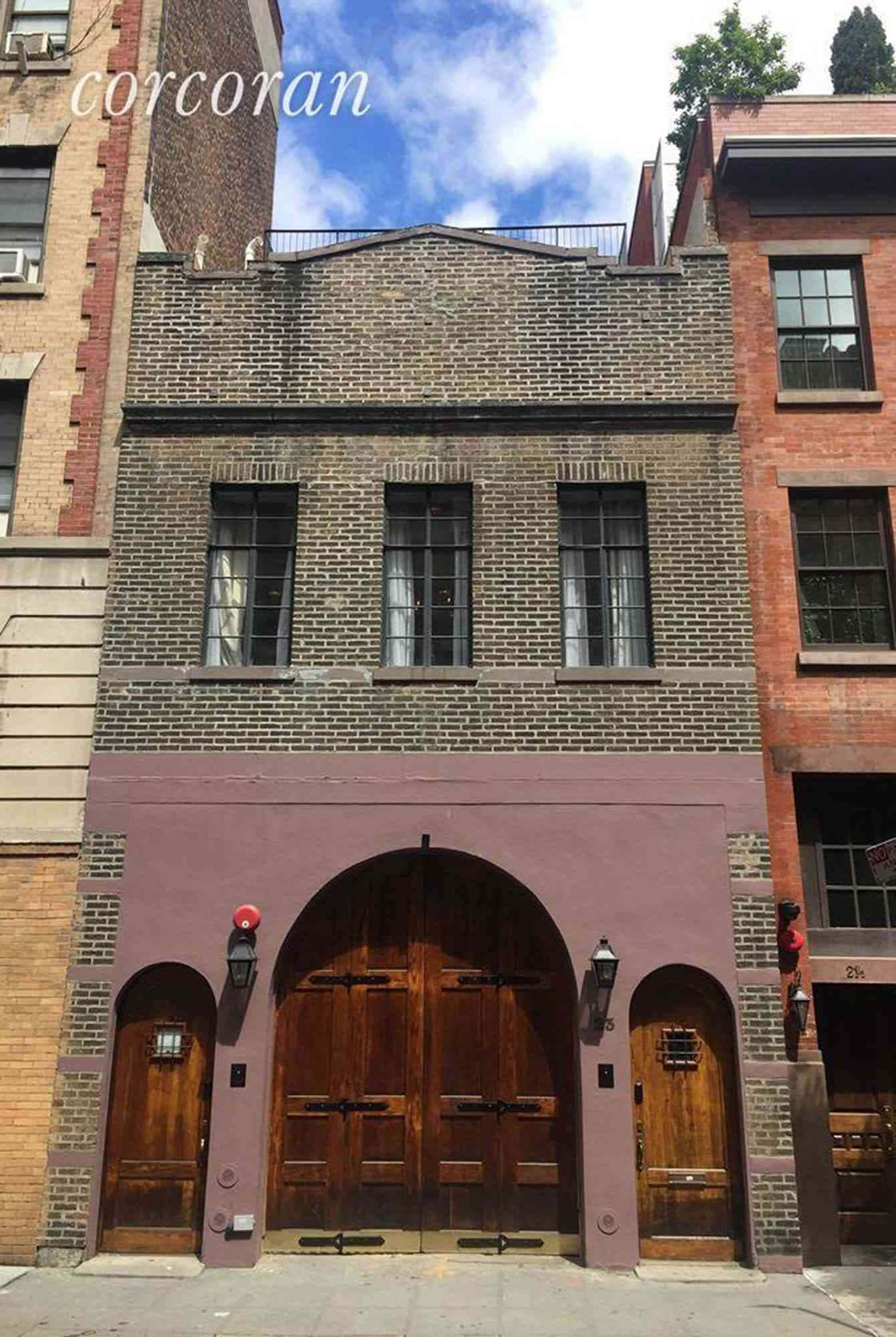 Street 桌布 壁紙 — 一座歷史悠久的磚砌建築，在陽光明媚的日子裡，紫色外牆下有一個大型拱形木門和較小的側門。