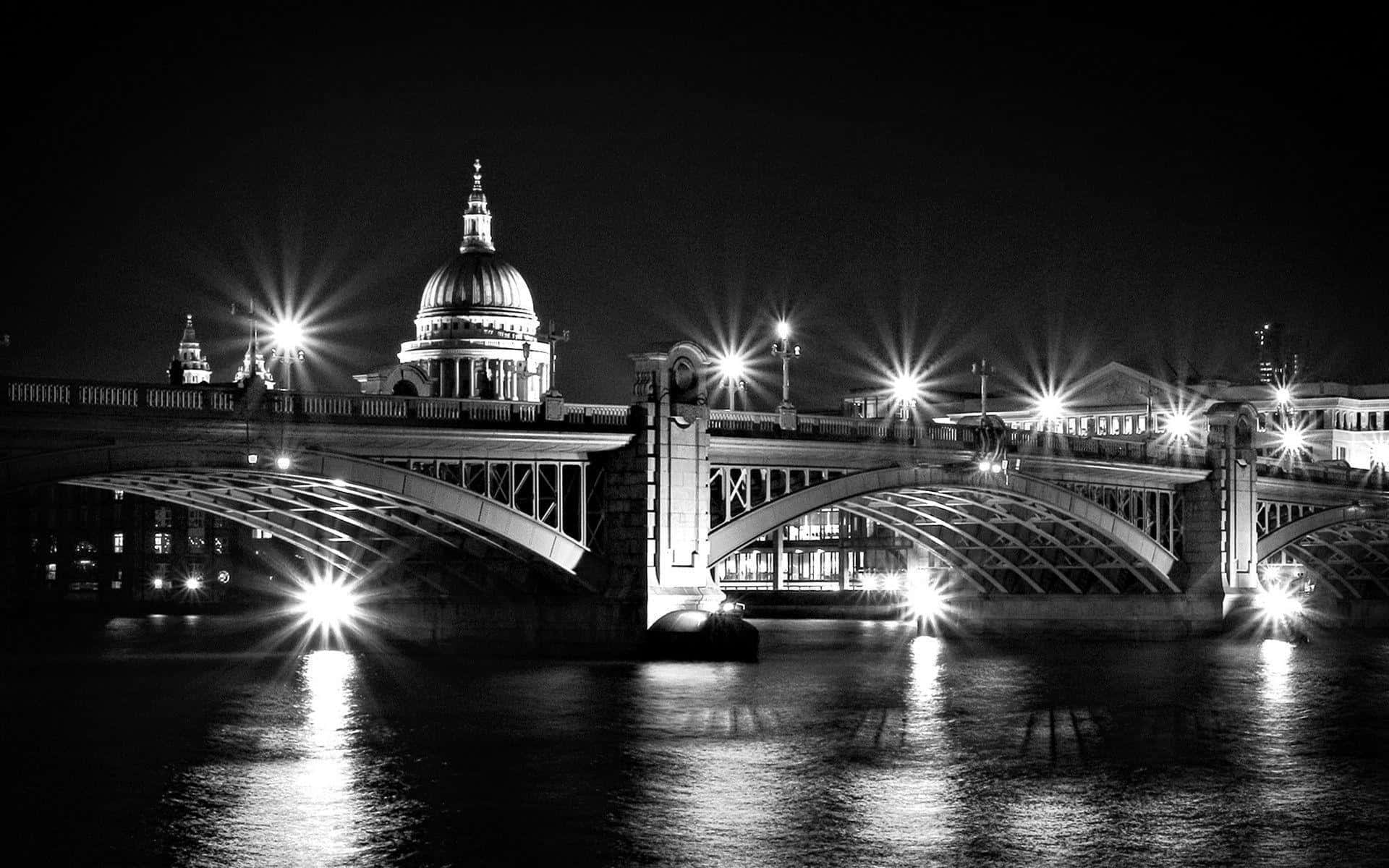 Black And White Architecture 桌布 壁紙 — 一座燈火通明的橋樑橫跨水面，背景有一座圓頂大教堂的黑白夜景。