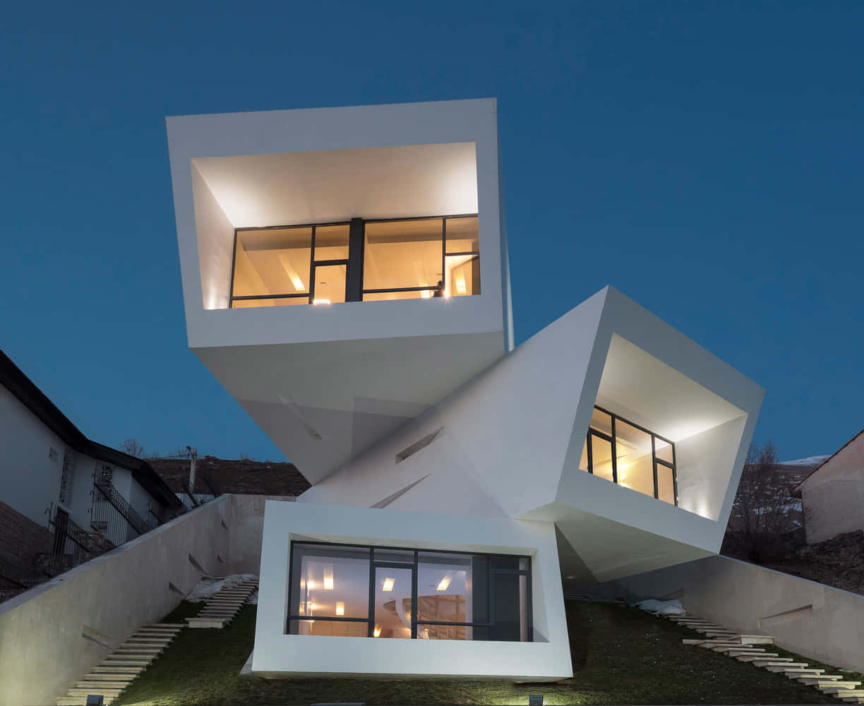 Minimalist Architecture 桌布 壁紙 — 一座現代白色幾何房屋，窗戶發光，矗立在深藍色的暮色天空下。