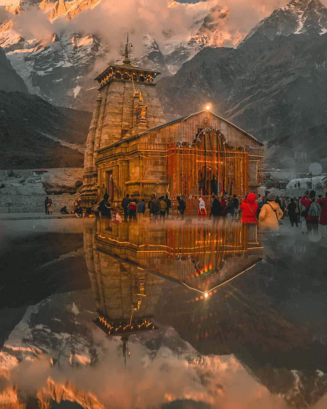 Kedarnath 桌布 壁紙 — 一座神聖的寺廟在黃金時段完美地倒映在平靜的水面上，周圍是白雪覆蓋的山脈和朝聖者。
