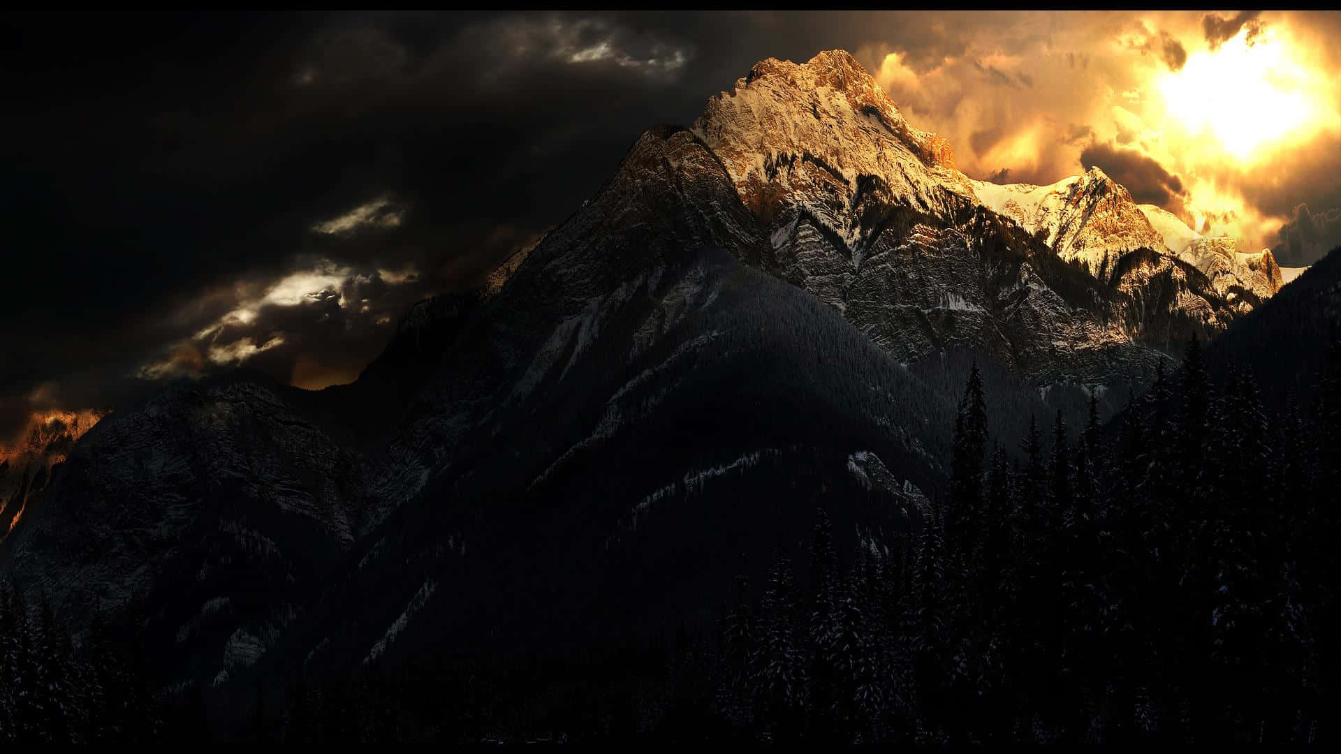 Dark Landscape 桌布 壁紙 — 一座積雪的山峰刺穿黑暗的暴風雲，金色的陽光從其後穿透，在前方的森林上投下戲劇性的陰影。
