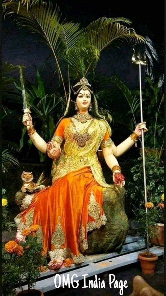 Goddess 桌布 壁紙 — 一座莊嚴的四臂女神雕像，以鮮豔的橙色和金色呈現，在夜晚的熱帶茂密植物中端坐在石製寶座上。