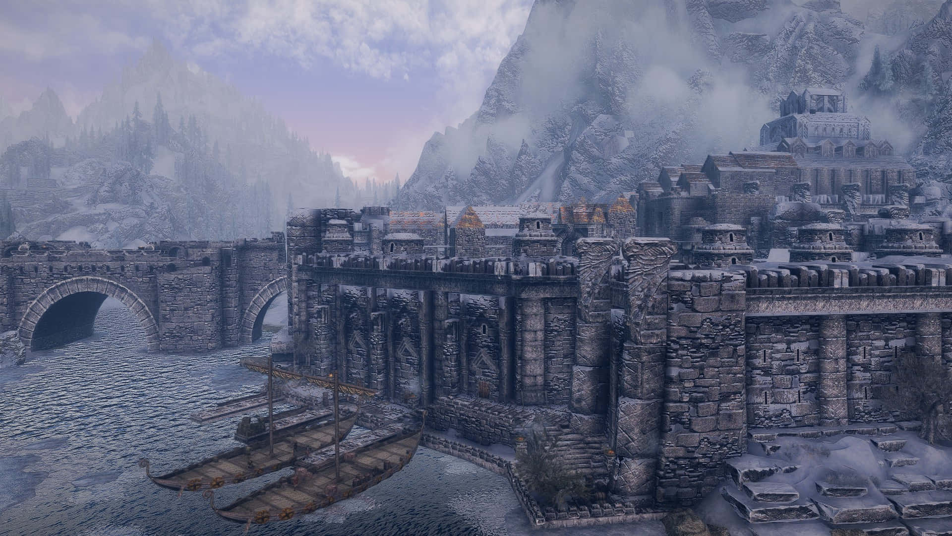 Skyrim Windhelm 桌布 壁紙 — 一座被雪覆蓋的中世紀堡壘城市，坐落在懸崖上，有石橋和船隻停泊在冰冷的 waters 中，天空籠罩著薄霧的暮色。