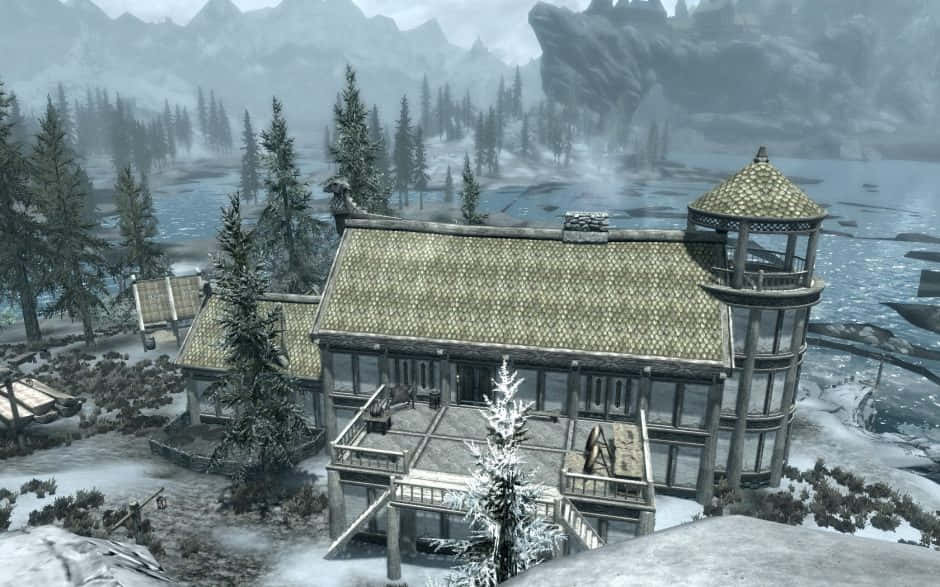 Heljarchen Hall 桌布 壁紙 — 一座被雪覆蓋的帶塔木屋矗立在結冰的湖邊，周圍環繞著松樹和霧氣繚繞的山巒。