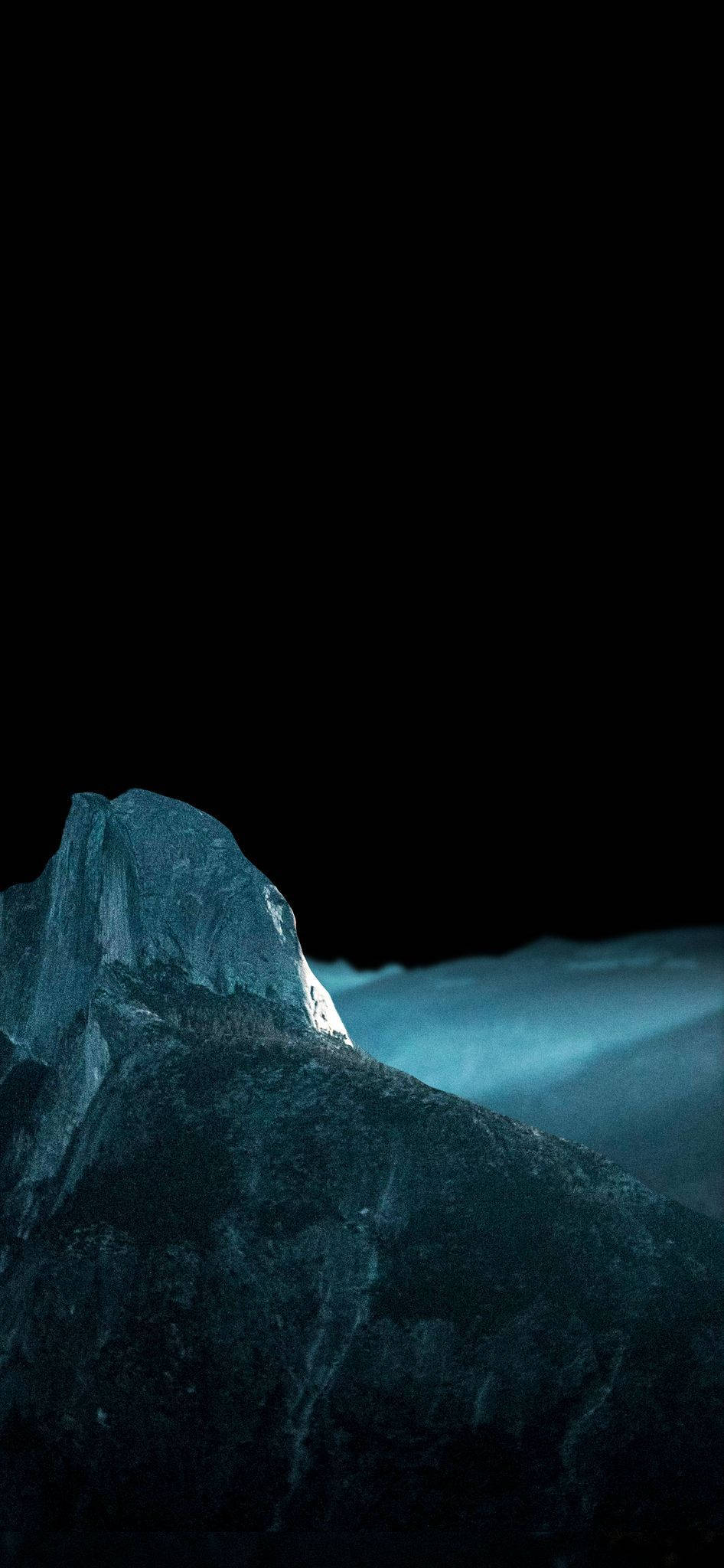冬天 桌布 壁紙 — 一座陡峭的山峰在漆黑天空和霧氣瀰漫的山谷上方散發著冰冷的藍光。