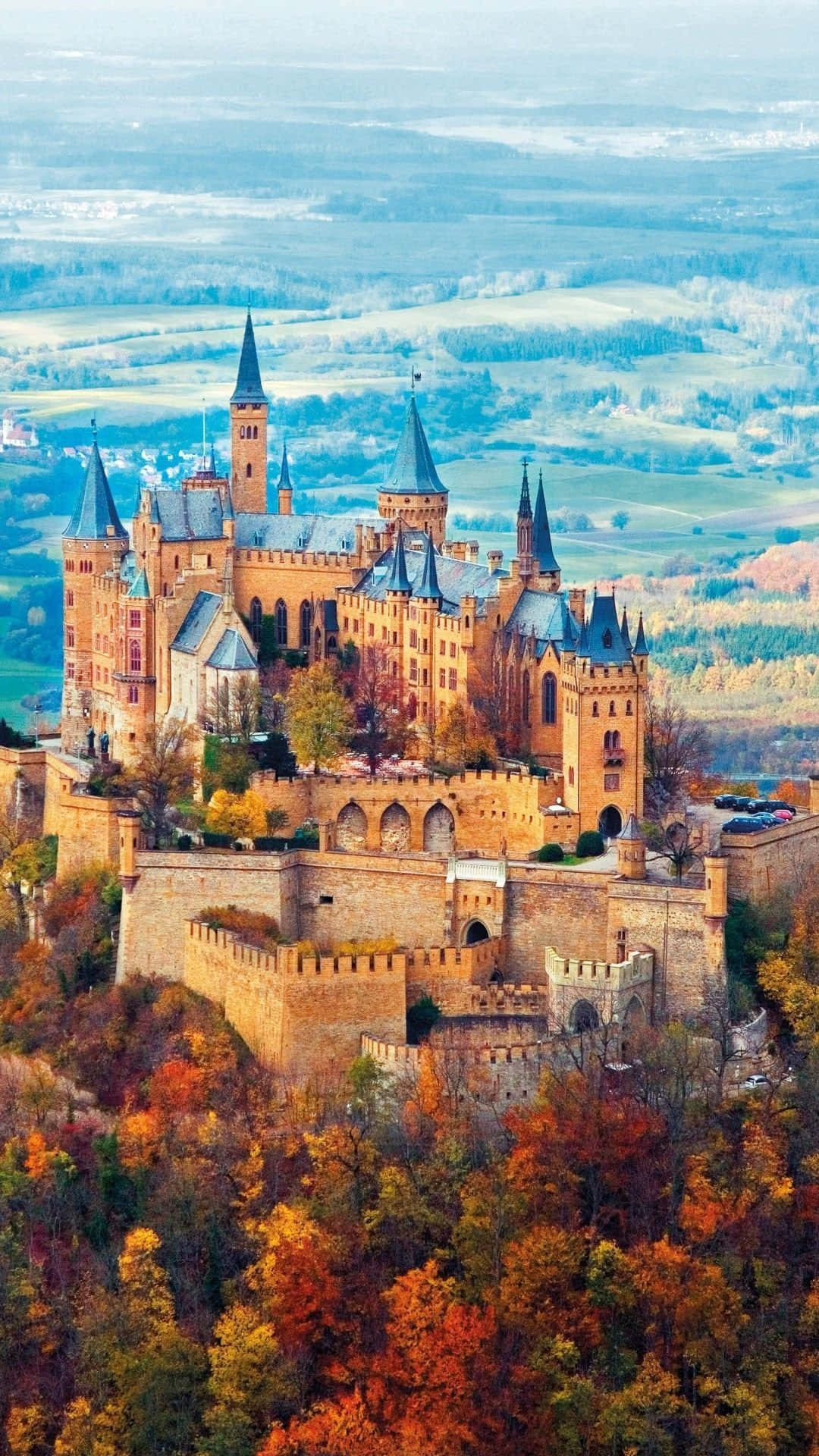 Germany 桌布 壁紙 — 一座雄偉的中世紀城堡，擁有尖塔和角樓，坐落在山頂上，周圍環繞著充滿活力的秋葉。