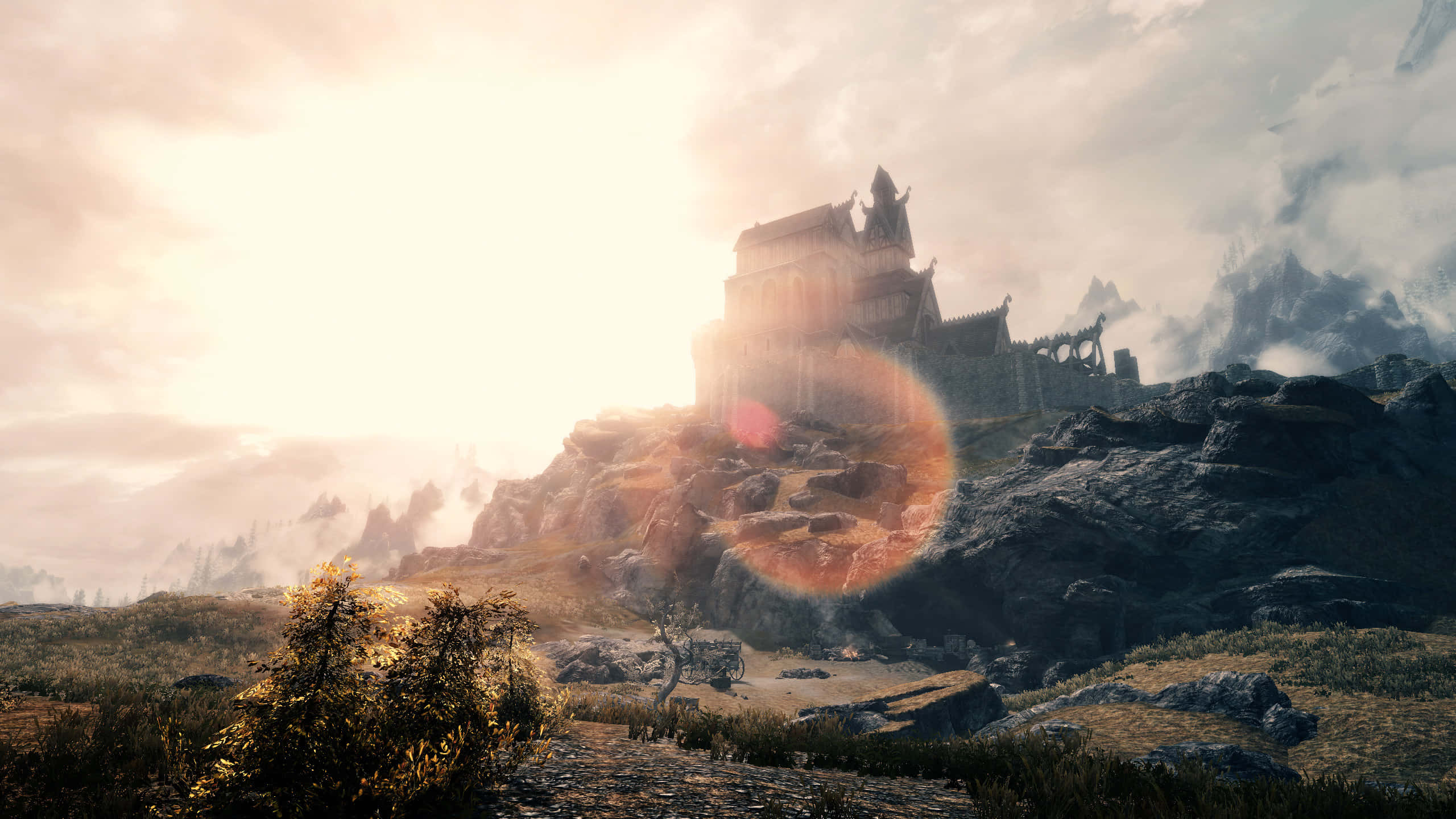 Skyrim Whiterun 桌布 壁紙 — 一座雄偉的城堡坐落在岩石懸崖頂上，沐浴在金色的日出光芒中，帶有鏡頭光暈和遠處霧氣繚繞的山脈。