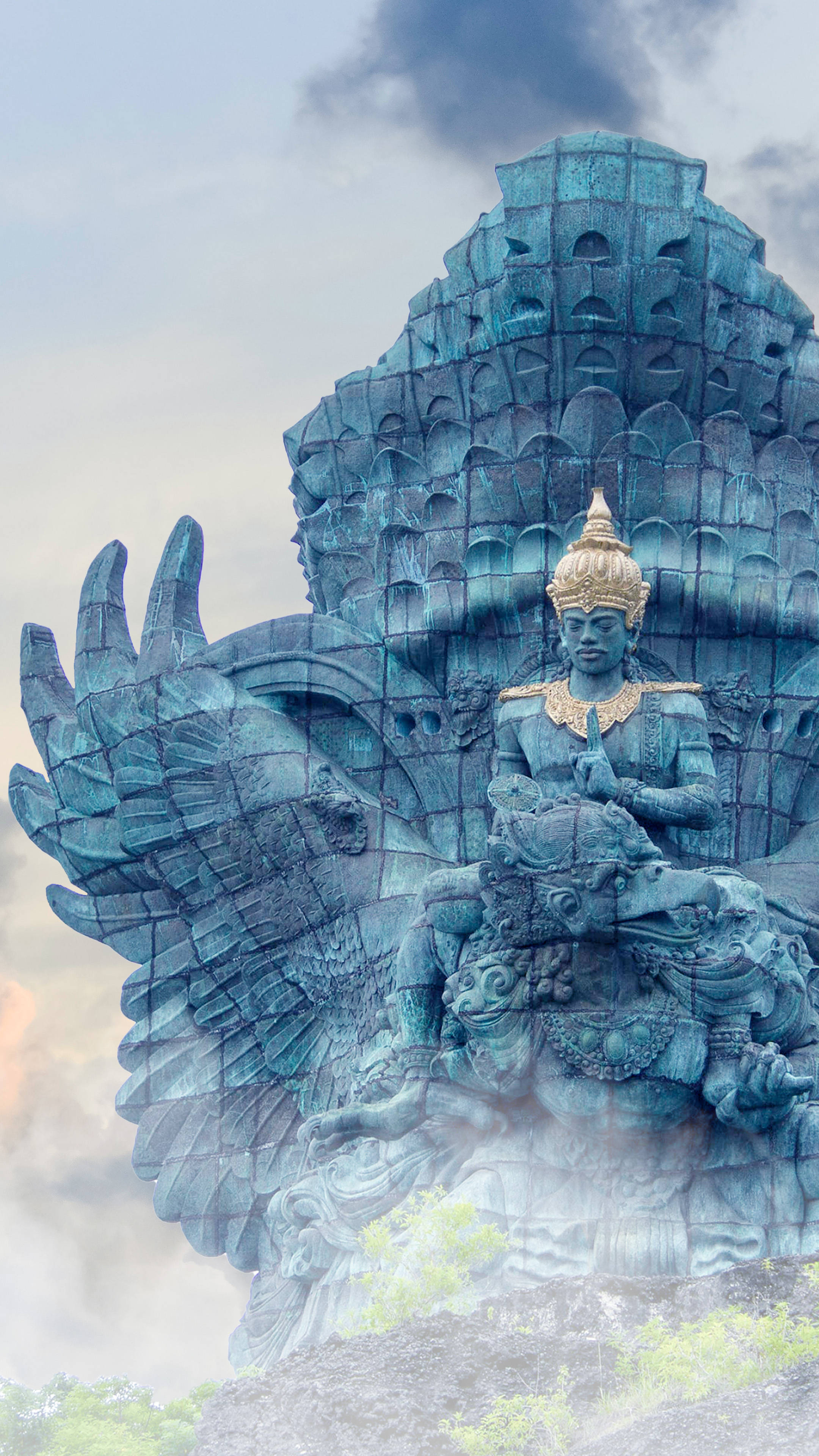 Hindu Temple 桌布 壁紙 — 一座雄偉的綠松石迦樓羅雕像，雕刻精細，頭戴金色皇冠，矗立在雲霧繚繞的天空下。