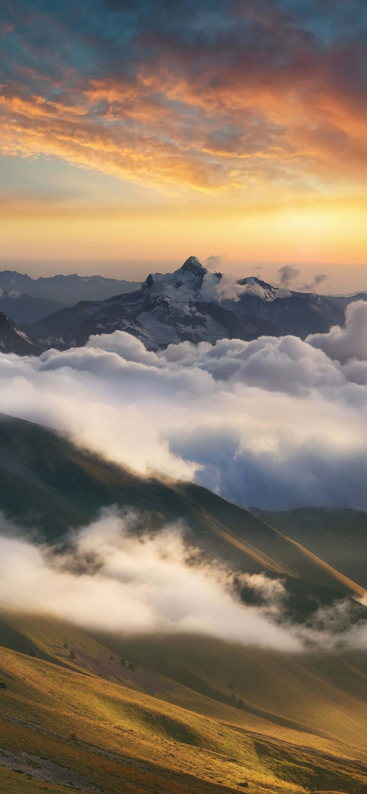 Panorama 桌布 壁紙 — 一座雄偉的雪山峰頂在日出時穿透雲層，金色的光芒沐浴著大地。