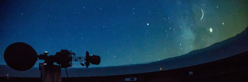 Planetarium 桌布 壁紙 — 一座電波望遠鏡在繁星點點的夜空下剪影，新月和發光的極光在遠山之上。