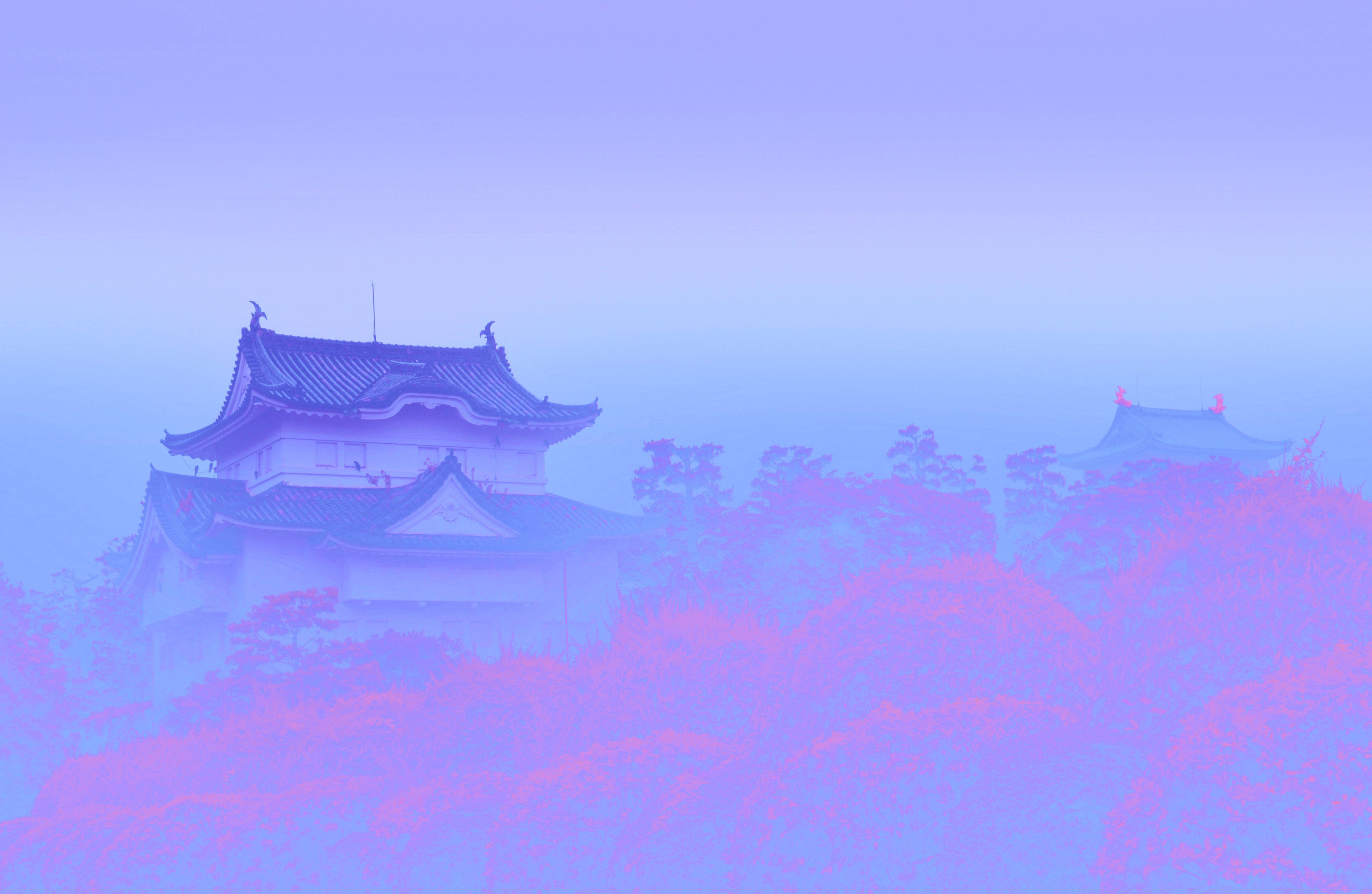 Japanese Aesthetic HD 桌布 壁紙 — 一座霧中的日本城堡從迷霧中浮現，超現實的紫色和粉紅色調沐浴著傳統建築和周圍的樹木。