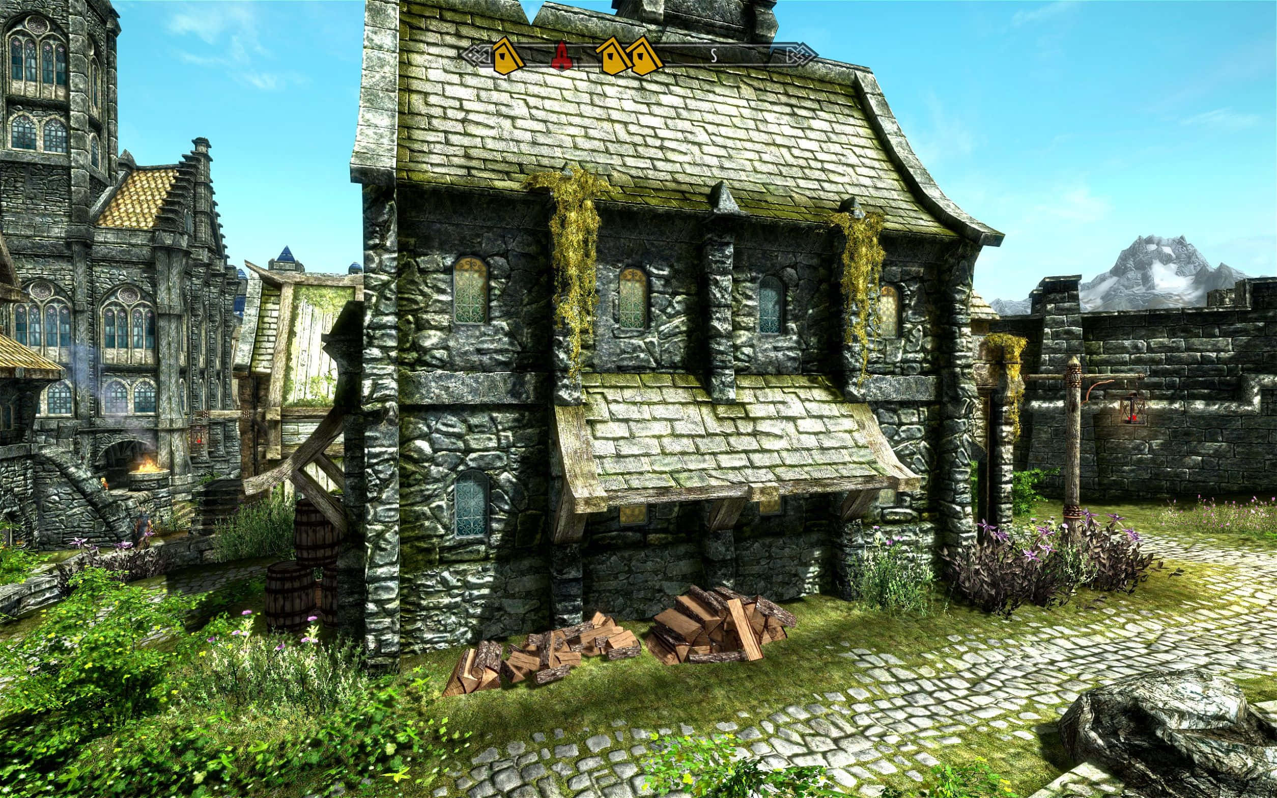 Skyrim Solitude 桌布 壁紙 — 一座風化的石屋，長滿青苔的屋頂和破損的磚塊，坐落在鵝卵石小徑上，旁邊是一座大教堂，在清澈的藍天下。