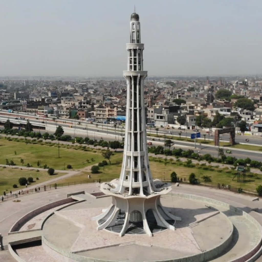Pakistan 桌布 壁紙 — 一座高大的白色宣禮塔矗立在圓形廣場上，城市景觀延伸至朦朧的遠方。