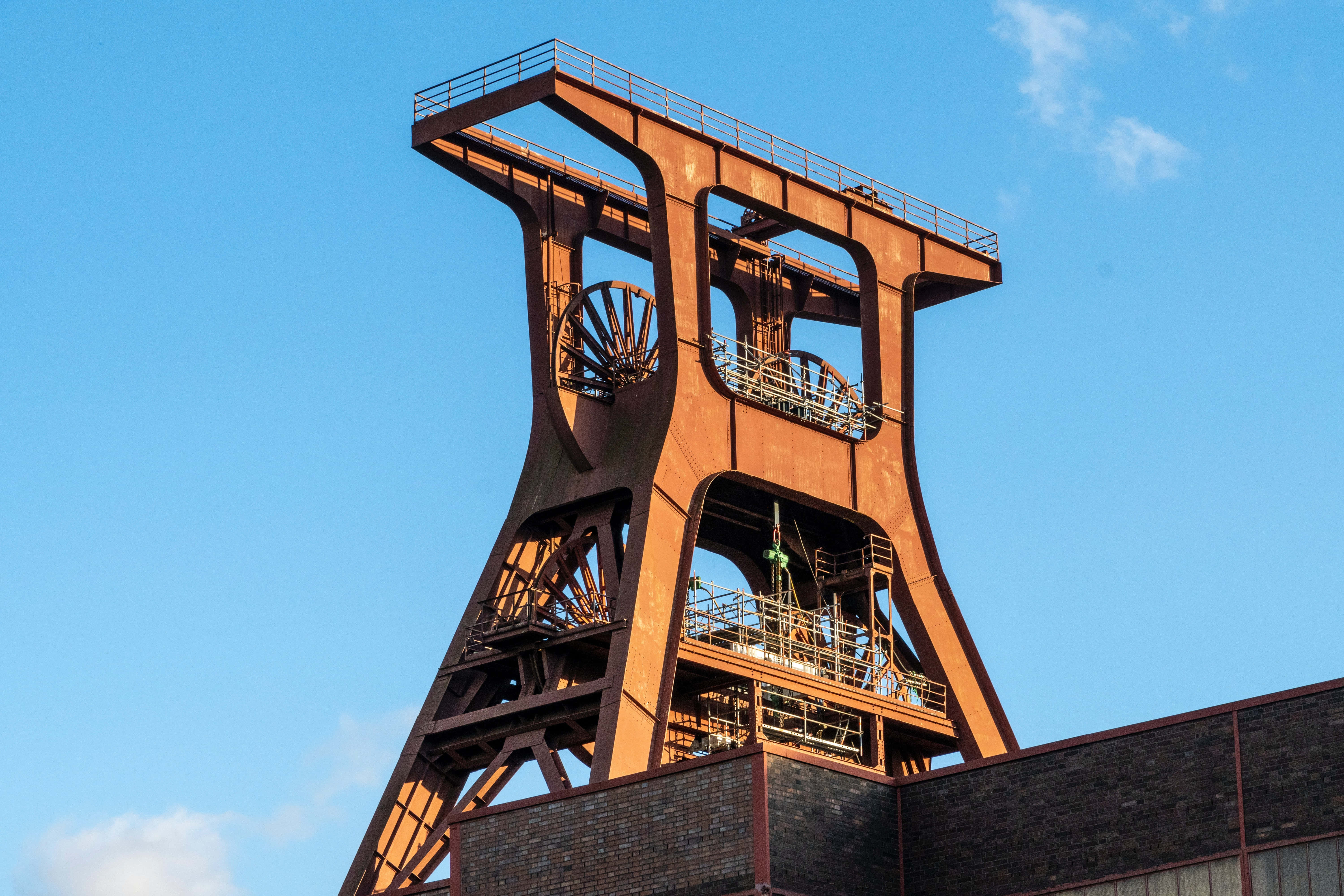 Mining 桌布 壁紙 — 一座高聳生鏽的礦井井架，矗立在藍天白雲之下。