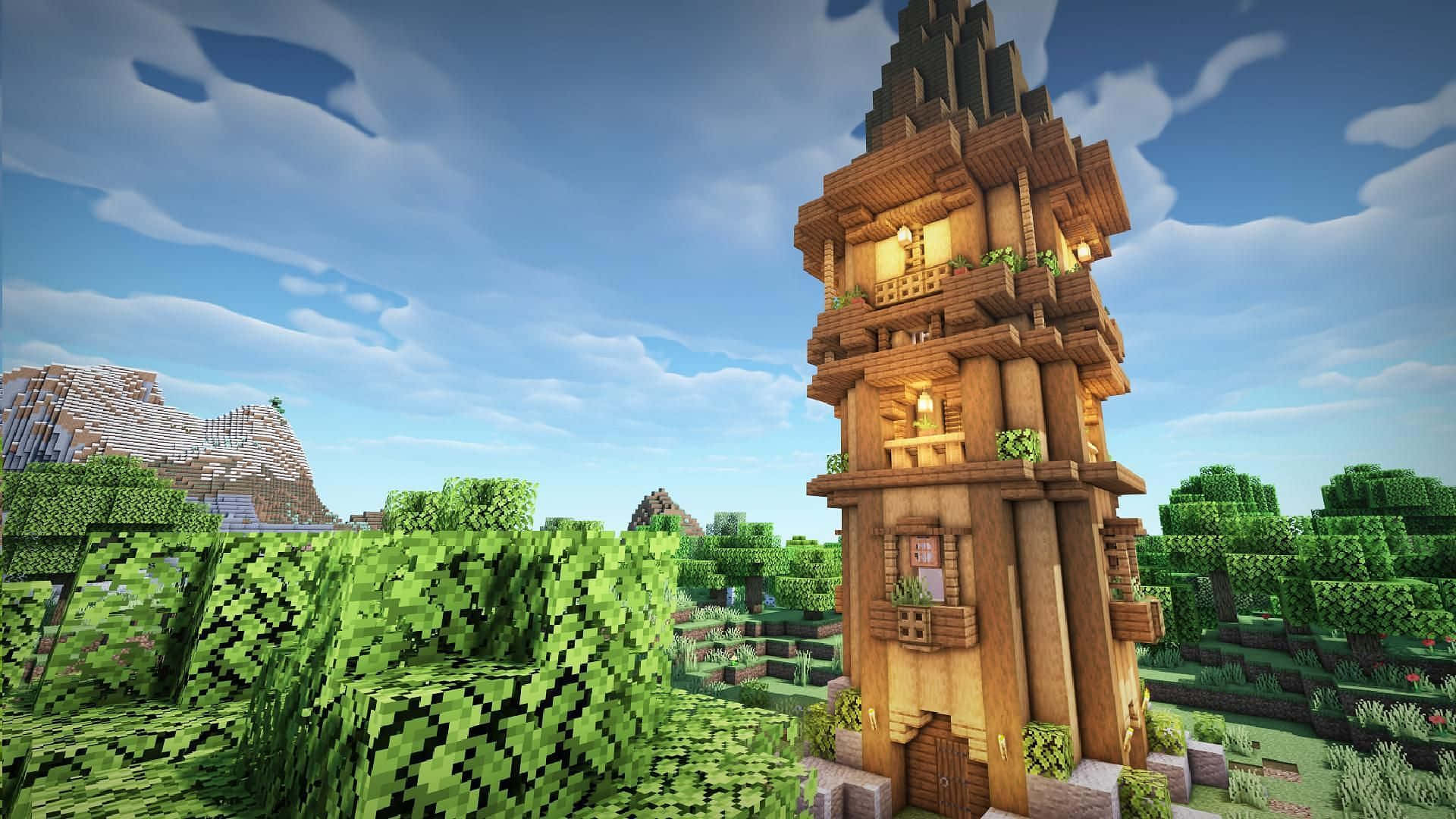Minecraft Building 桌布 壁紙 — 一座高聳的木製Minecraft房屋，帶有發光的窗戶，矗立在茂密的綠色像素化森林中，天空湛藍明亮。