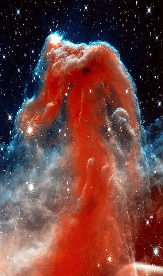 Interstellar Cloud 桌布 壁紙 — 一座高聳的紅色和藍色宇宙氣體和塵埃柱，由明亮的星星照亮，背景是繁星點點的黑色天空。
