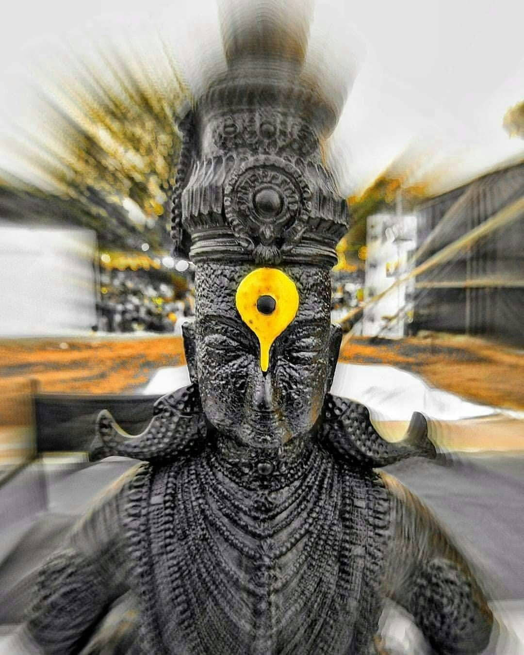 Hindu Temple 桌布 壁紙 — 一座黑暗雕像，帶有發光的黃色第三隻眼，在動態模糊的背景前散發神聖能量。