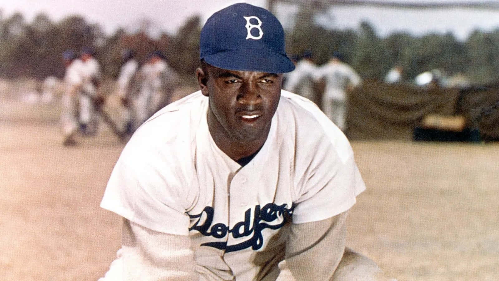 Jackie Robinson 桌布 壁紙 — 一張Jackie Robinson身穿道奇隊球衣蹲在棒球場上的復古照片，背景有隊友。