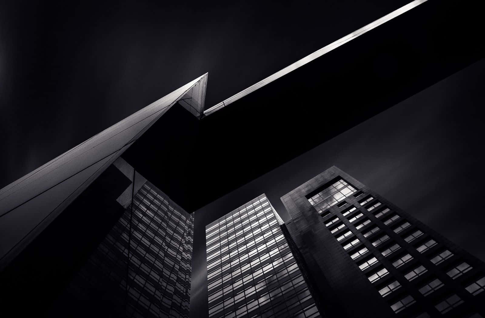 Black And White Architecture 桌布 壁紙 — 一張低角度拍攝、戲劇性的黑白照片，高聳的摩天大樓在黑暗的天空下匯聚，伴隨一道明亮的水平光條。