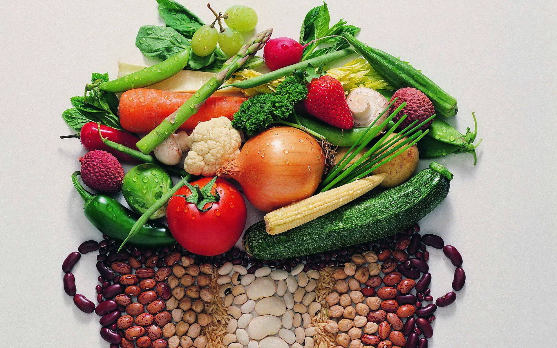 Vegetable 桌布 壁紙 — 一張充滿活力的俯拍照片，展示各種新鮮蔬菜、水果和豆類在白色背景上排列成色彩繽紛的心形。