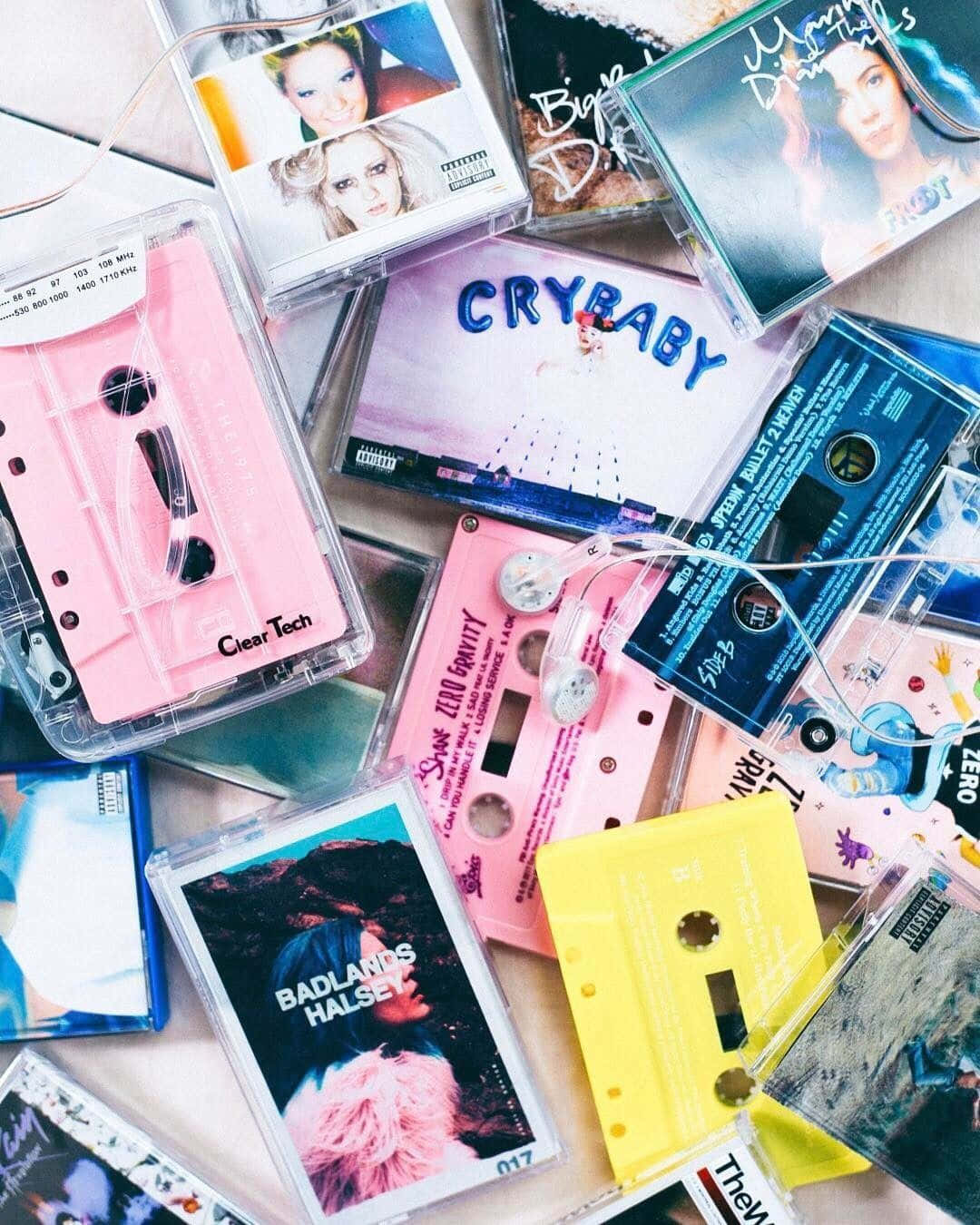 90's Vintage Retro Aesthetic 桌布 壁紙 — 一張充滿活力的俯拍照片，展示色彩繽紛的卡式錄音帶，上面散落著專輯藝術圖案，置於淺色表面上。