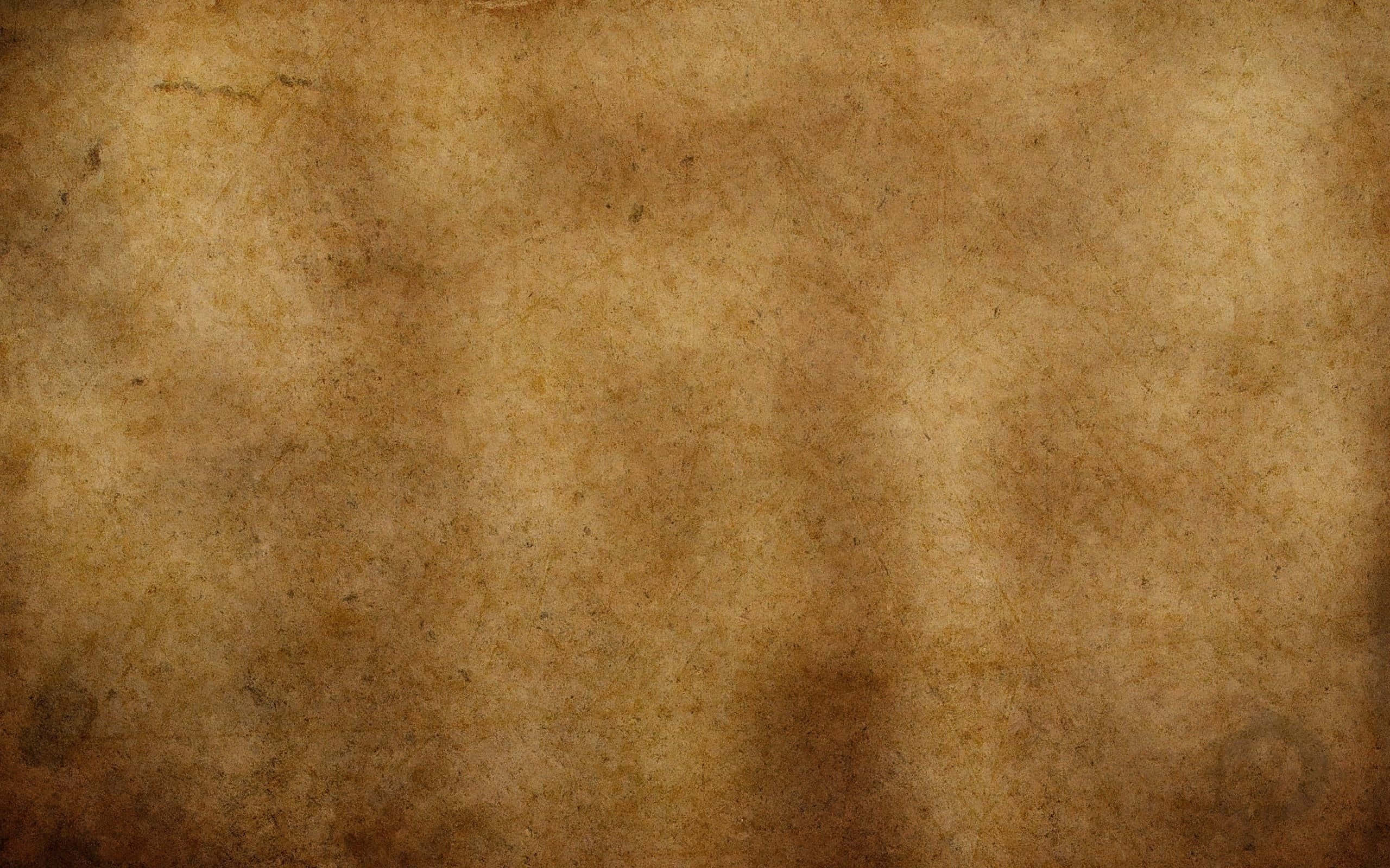 Brown Vintage 桌布 壁紙 — 一張古老羊皮紙的特寫，帶有不均勻的棕色污漬和微妙的紋理變化。