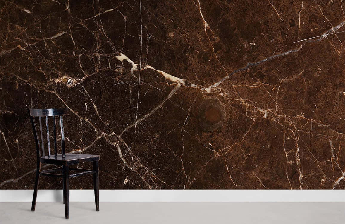 Brown Marble 桌布 壁紙 — 一張孤獨的黑色椅子矗立在帶有金色紋理和自然圖案的濃郁棕色大理石牆前。