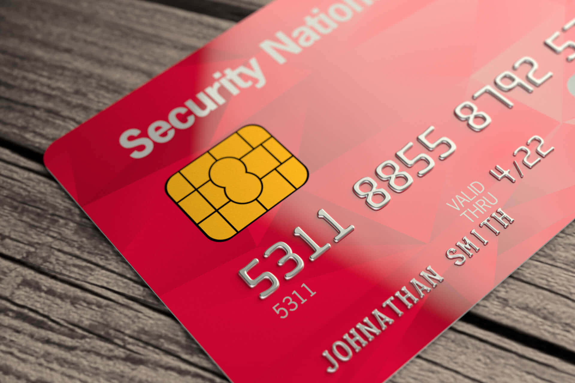 Credit Card 桌布 壁紙 — 一張帶有金色晶片和銀色文字的紅色信用卡，斜放在風化的木板上。