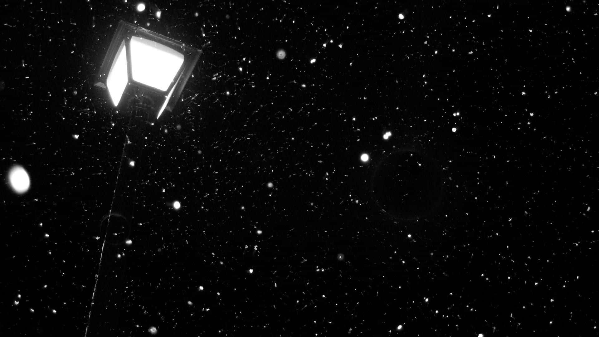 Dark Sky 桌布 壁紙 — 一張強烈對比的黑白照片，捕捉了在飄雪的夜空下發光的街燈。