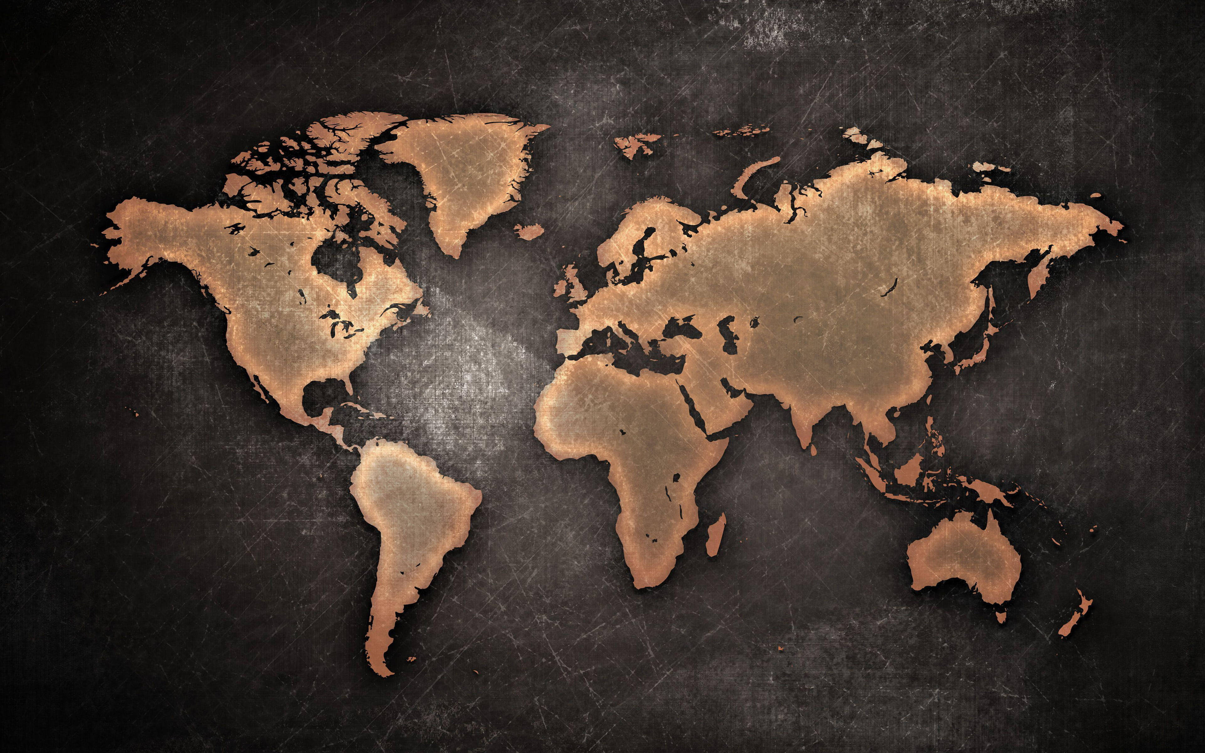 世界地圖 桌布 壁紙 — 一張復古銅色世界地圖蝕刻在深色紋理表面上，帶有可見的刮痕和磨損。