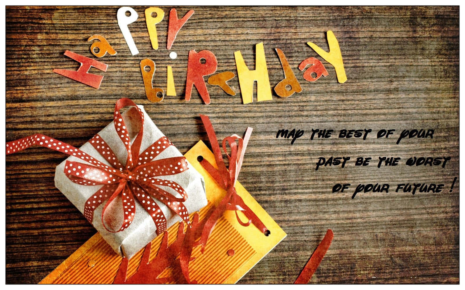 Birthday Wishes 桌布 壁紙 — 一張手工製作的生日卡，上面有彩色紙字母和一個用紅色圓點絲帶包裝的禮物，背景是質樸的木頭。