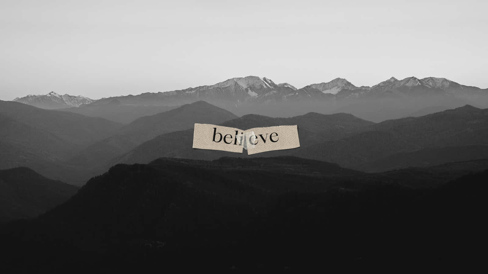 黑白美學 桌布 壁紙 — 一張撕破的紙上寫著「believe」，漂浮在單色風景中層疊的山脈之上。
