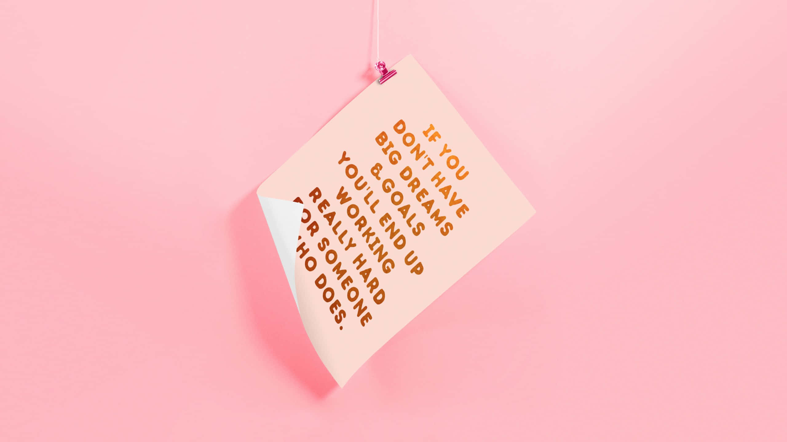 Minimalist Quote 桌布 壁紙 — 一張桃色便利貼上寫有勵志文字，用粉紅色夾子掛在柔和粉紅色背景上。