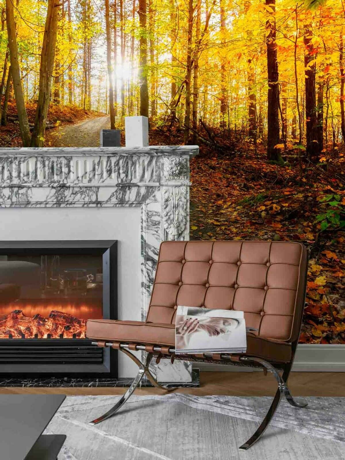 Autumn Fireplace 桌布 壁紙 — 一張棕色皮革椅放在大理石壁爐前，爐火餘燼發光，背景是充滿活力的秋日森林壁紙，有金色樹葉和陽光光束。