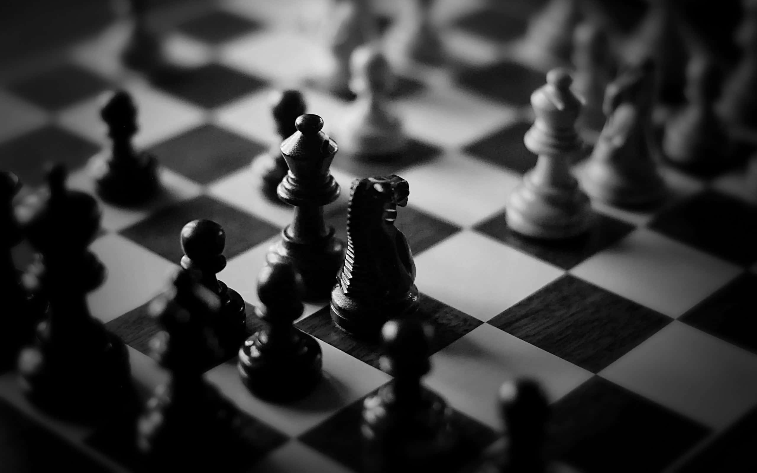 Black And White Chess 桌布 壁紙 — 一張淺景深黑白照片，顯示木製棋盤上的國際象棋棋子，騎士處於焦點。