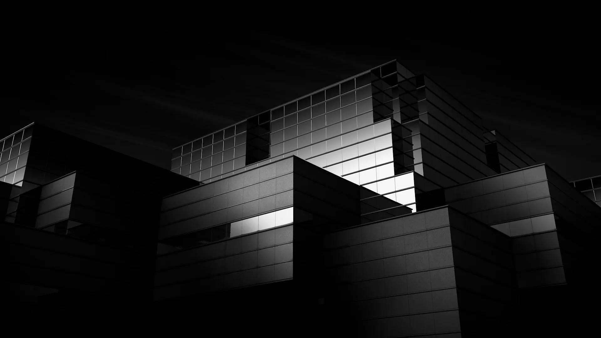 Building 桌布 壁紙 — 一張清晰的黑白建築攝影，捕捉現代建築在夜晚的模樣，發光的窗戶穿透深邃的陰影。