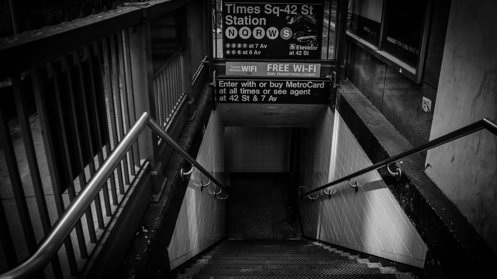 Subway 桌布 壁紙 — 一張清晰的黑白影像，展示通往時代廣場42街地鐵站的入口樓梯，附有方向標誌。
