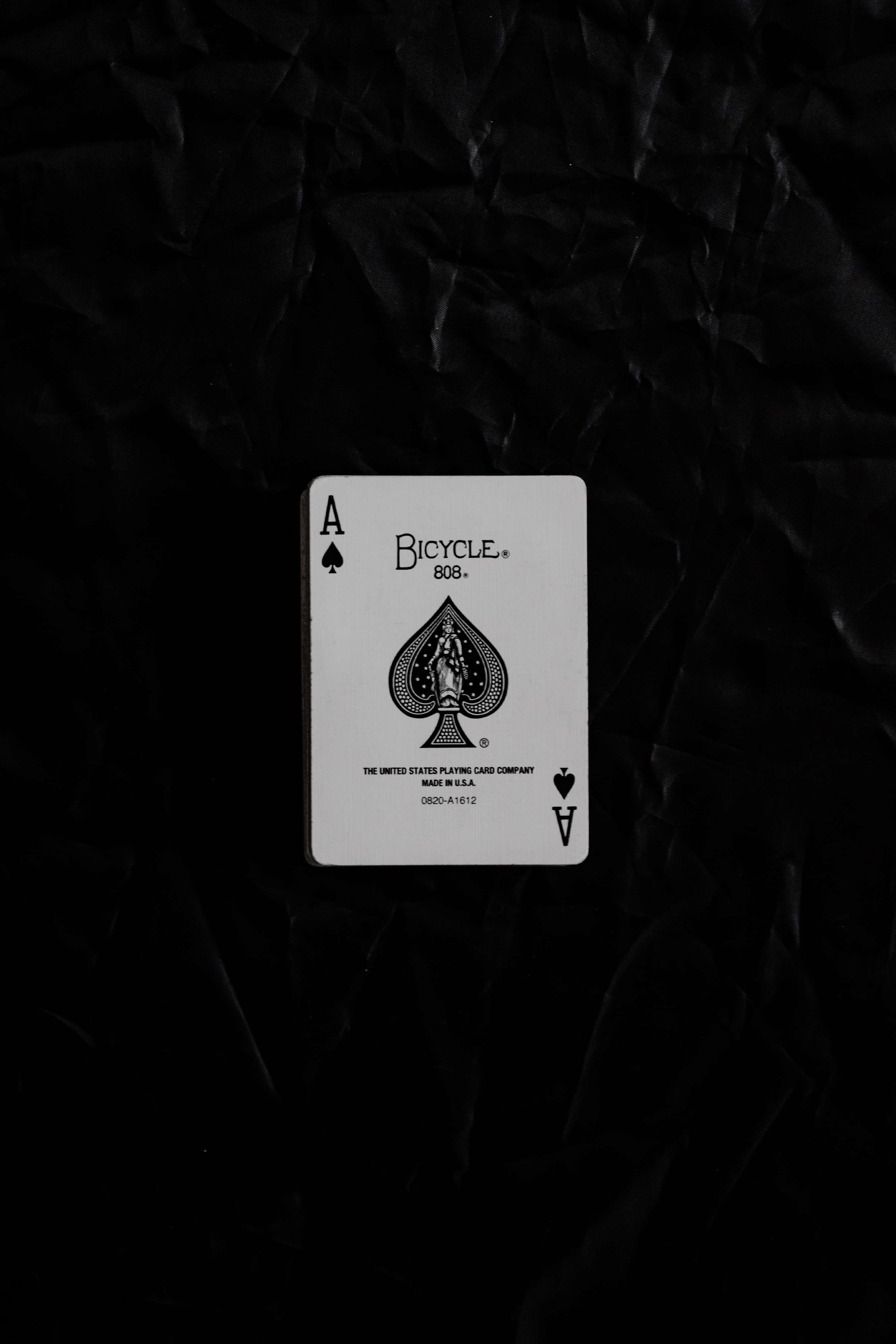 Playing Cards 桌布 壁紙 — 一張白色Bicycle黑桃A撲克牌居中放置在帶紋理的黑色皺摺表面上。